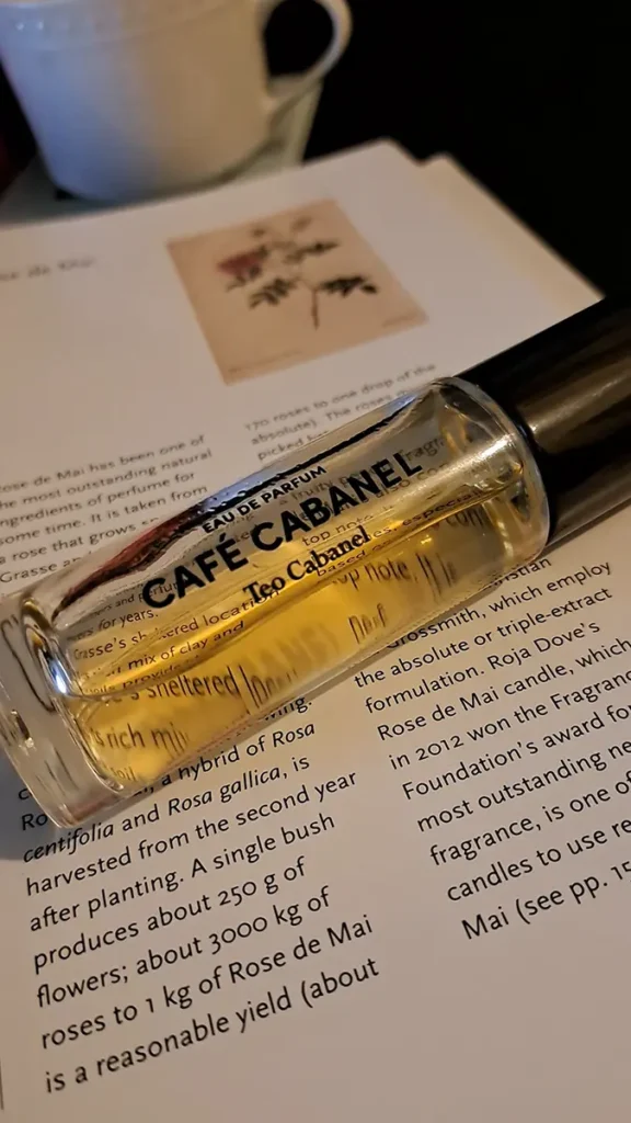 Close-up of a Café Cabanel perfume bottle on an open book page about fragrance notes.